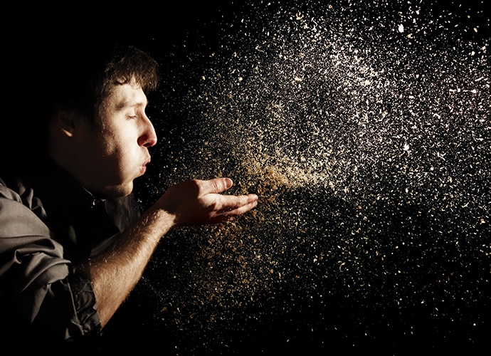 A man is blowing dust on his hand