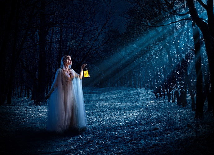 An actor holding a lamp in forest