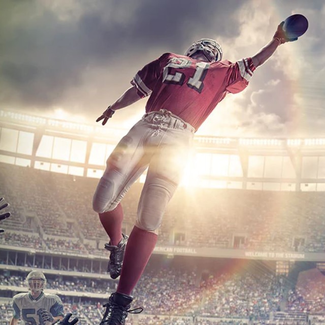 American football player jumping and reaching for the football