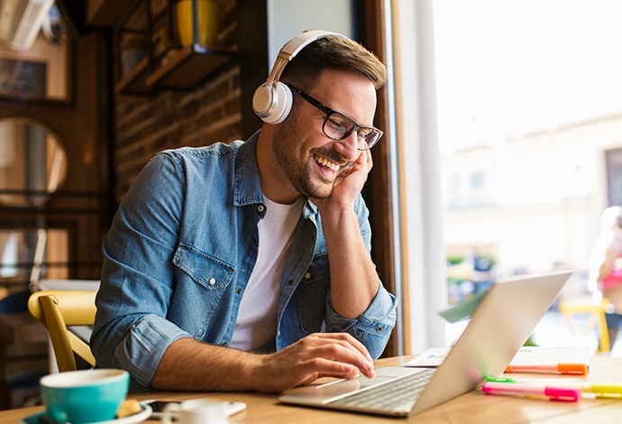 Guy with headphones laughing at laptop