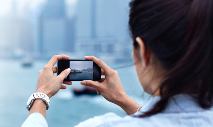 Female taking a picture of a river skyline with her cellphone