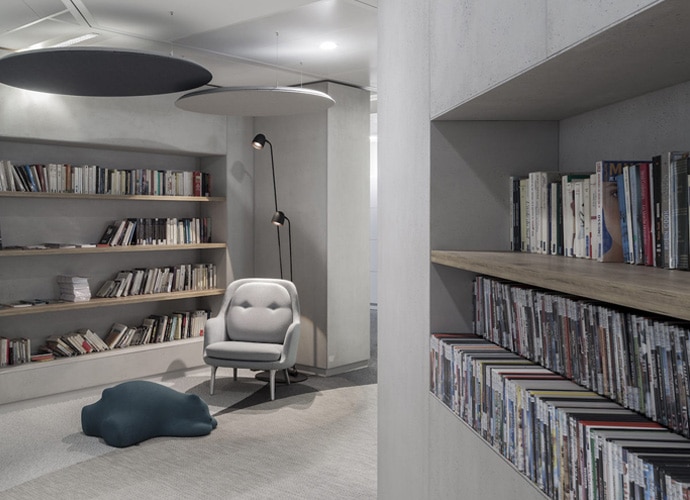 Image showing a relaxation space from within the office. An armchair is visible, along with a vast collection of books.