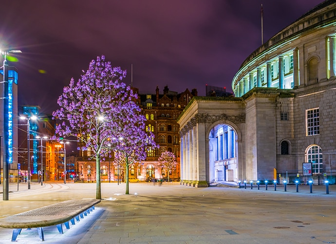 Illustrative image showing a clear footage of a city center at night lit up by lights from shops and buildings