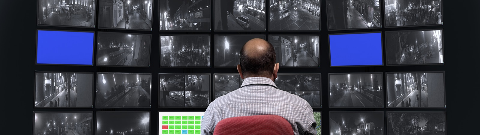 Man viewing video feed from security camera on a multi screen display