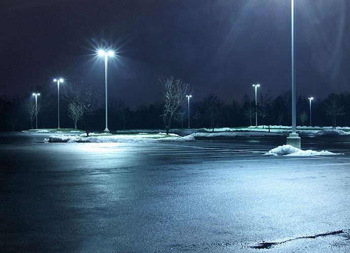 An empty parking lot at night with snow piled on the sides