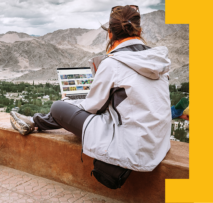 A woman works on laptop in a remote location, collaborating with others using the power of the cloud