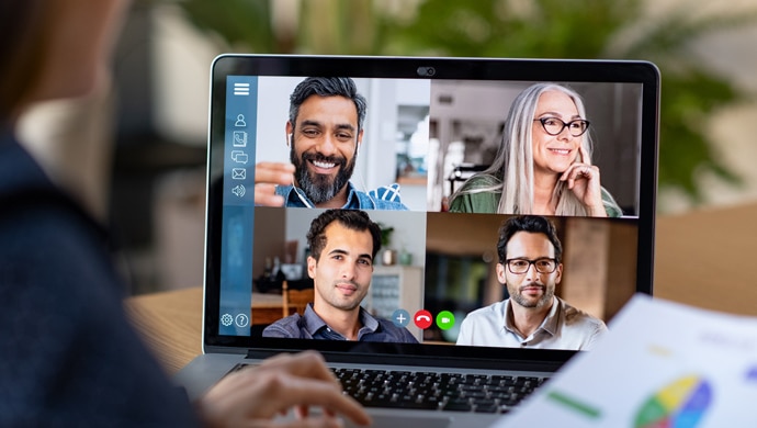 A laptop screen at a home desk showing four users on a video call together