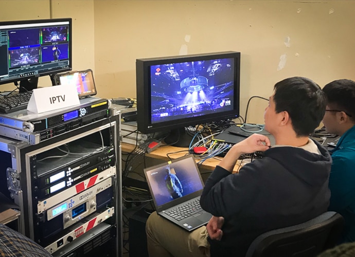 2 Chinese men watching the filming via a screen