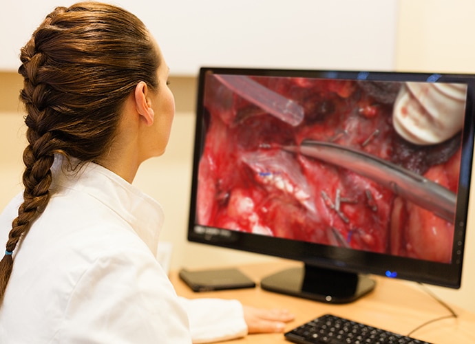 Female doctor viewing surgical footage on a desktop monitor