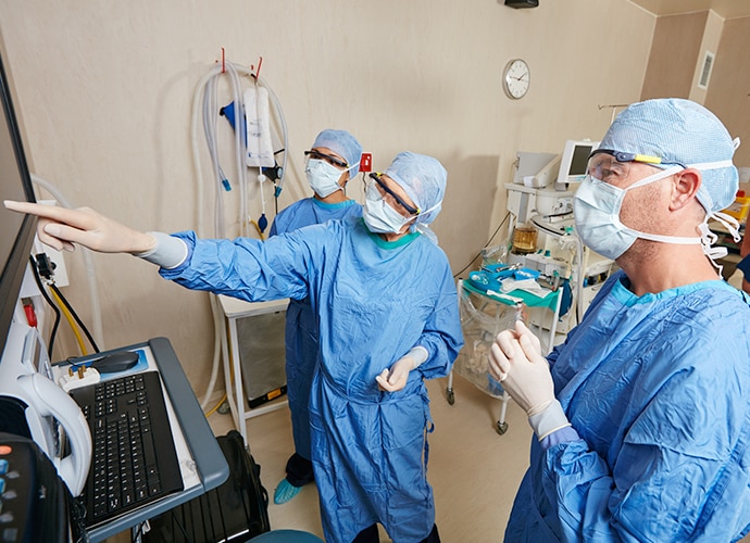 Three surgeons in active discussion in front of a display