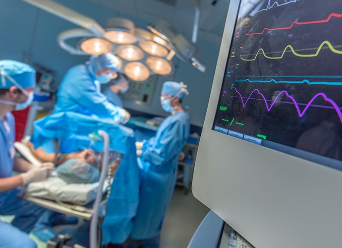 View of an OR showing surgery in progress and monitors showing vital signs