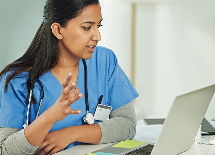 A female doctor in gesturing as she talks to someone on her laptop