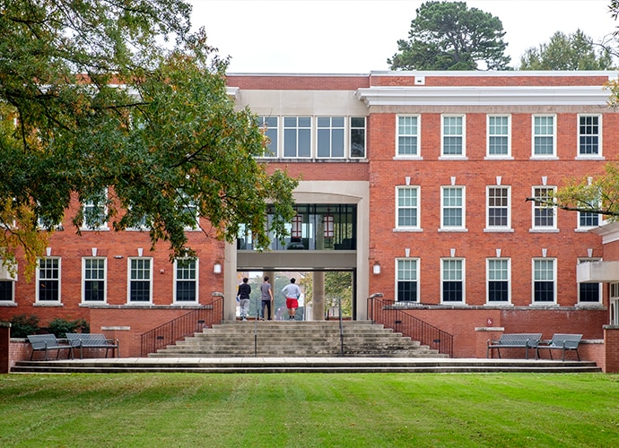 University of North Carolina Greensboro building with three students on top of the stairs