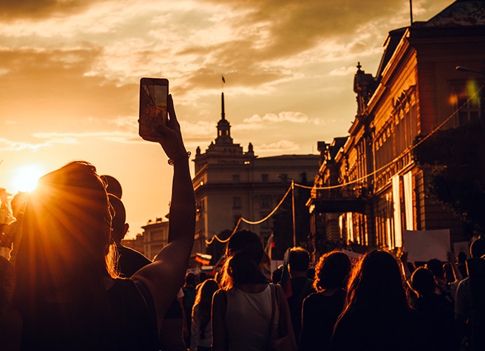 A crowd of people filming the sky at sunset with their mobile phones