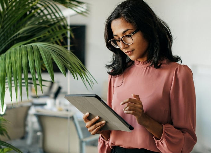 woman standing in an office environment looking at her ipad