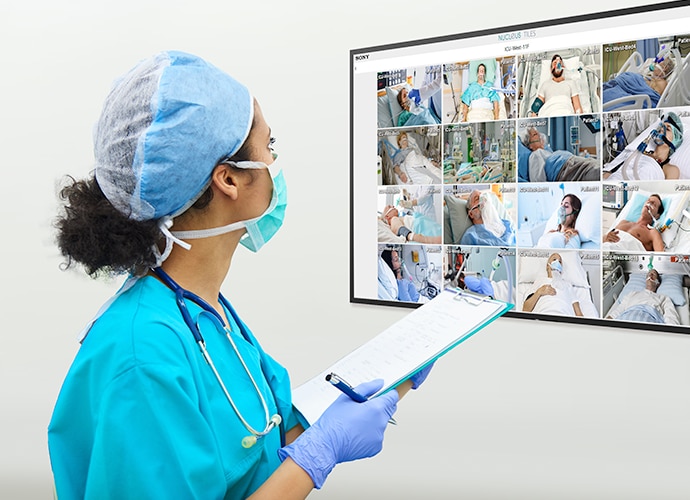 Doctor checks display with critical patients in the ICU displayed in mosaic view