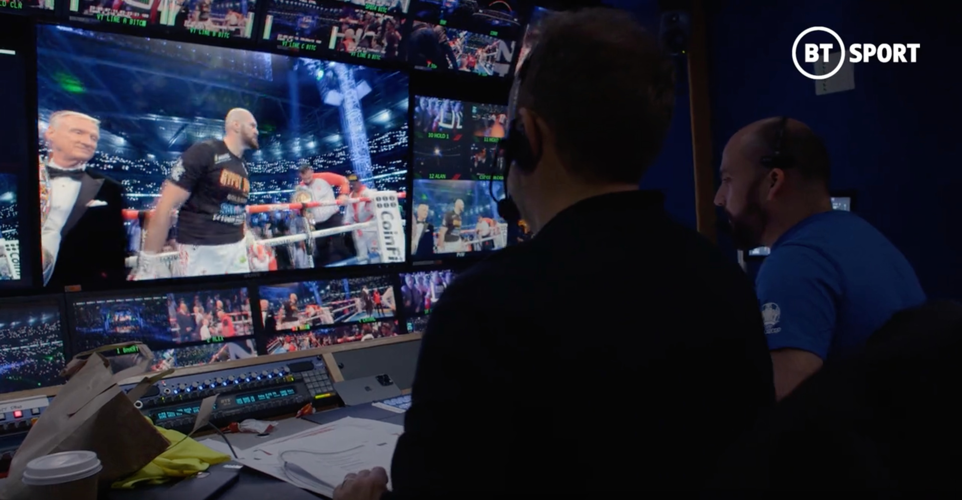 An image with comentator box with many screens that broadcast Tyson Fury and Dillian Whyte fight