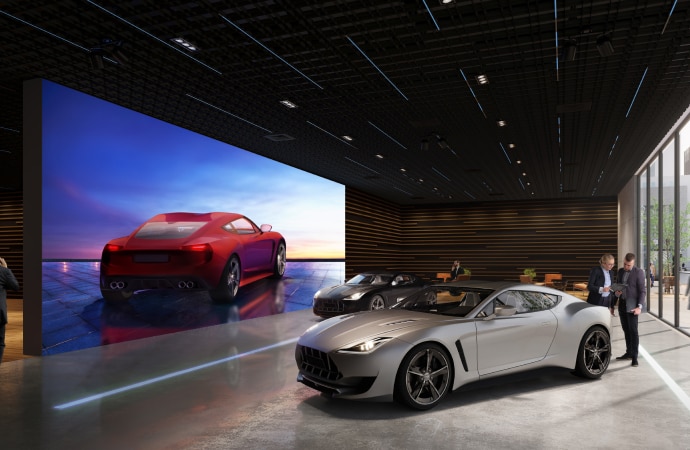 Image of a car show room with a large screen showing a car on it