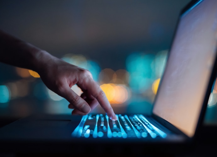 A finger touching a key on a laptop.