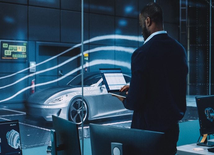 A man holding a laptop and looking at a car