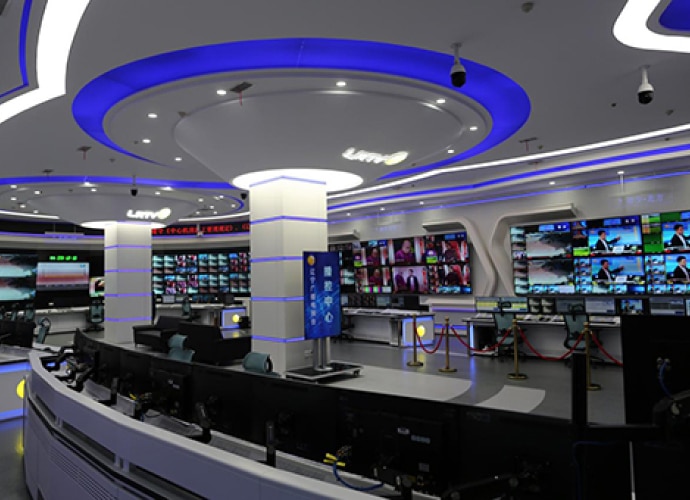 Side view of broadcast studio center with curved mosaic wall using large number of Bravia screens