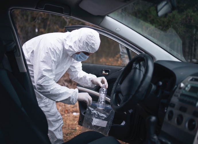 Forensic specialist is gathering evidence from the car.