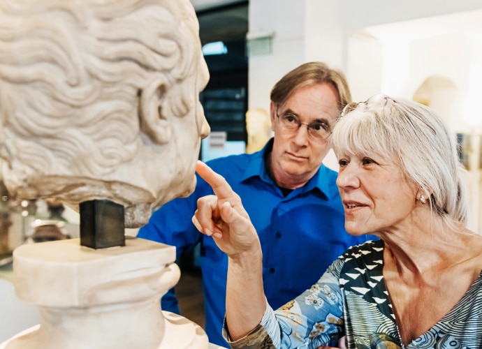 A woman and a man pointing at a sculpture.