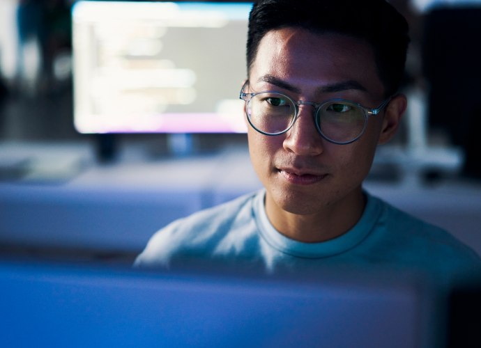 A man wearing glasses in front of a computer.