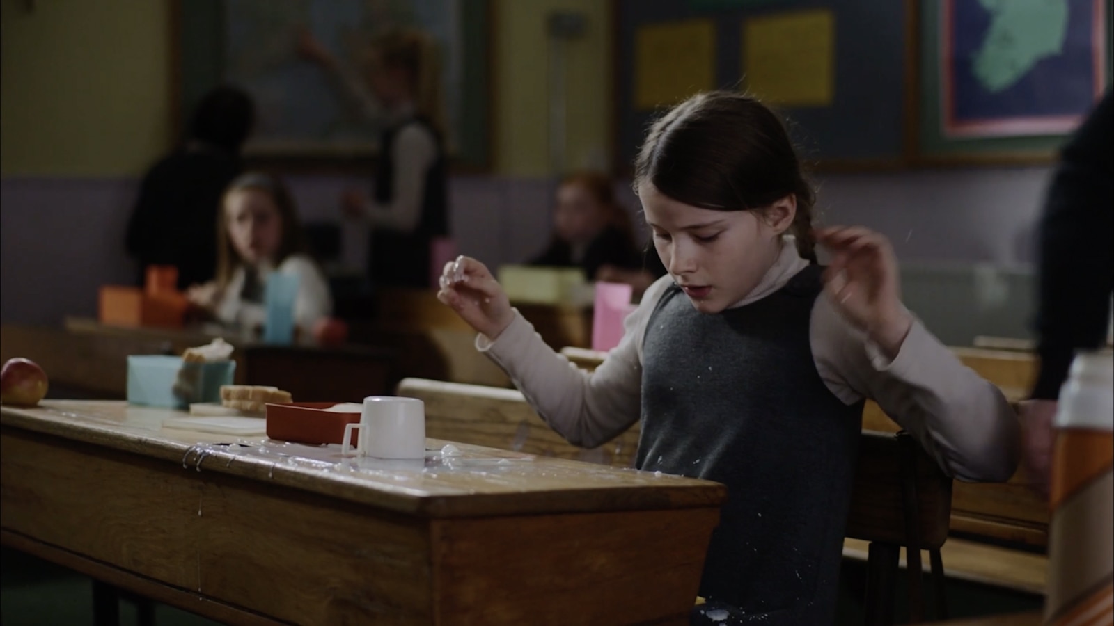 Cáit at school desk with water spilling