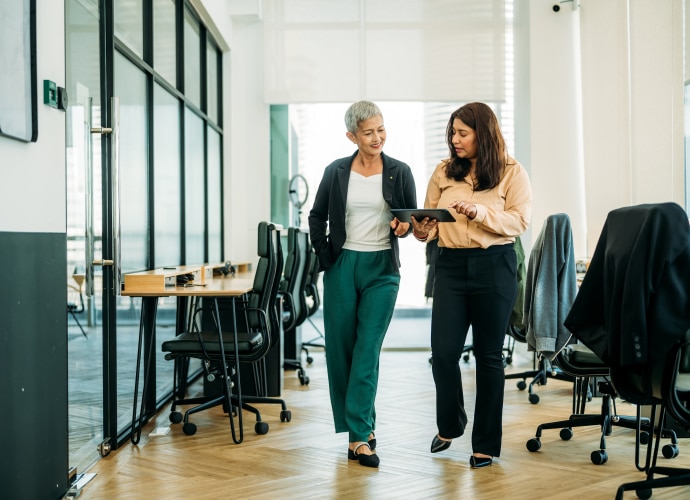 2 people walking through office with tablet in hand