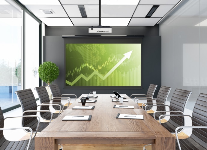 Meeting room with large display showing green graph with upwards arrow