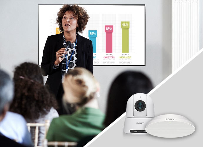 Woman presenting with a large screen behind her Product images of PTZ camera and microphone in the foreground