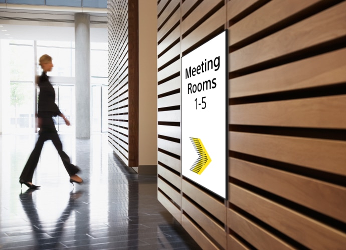 Office corridor with screen showing Meeting rooms numbers and direction