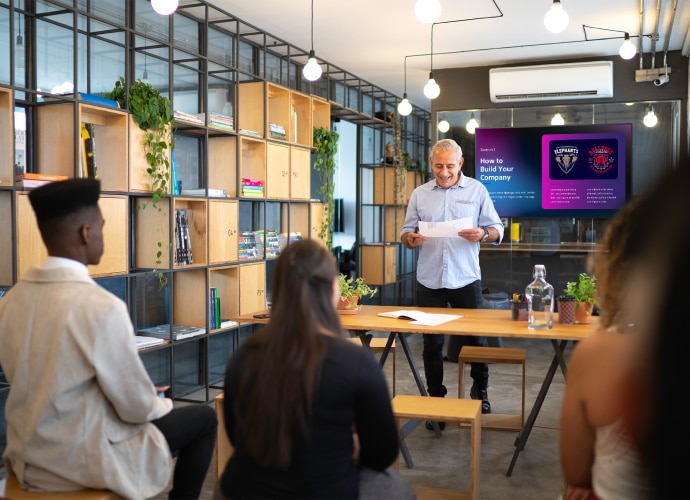 Man presenting with display screen behind him