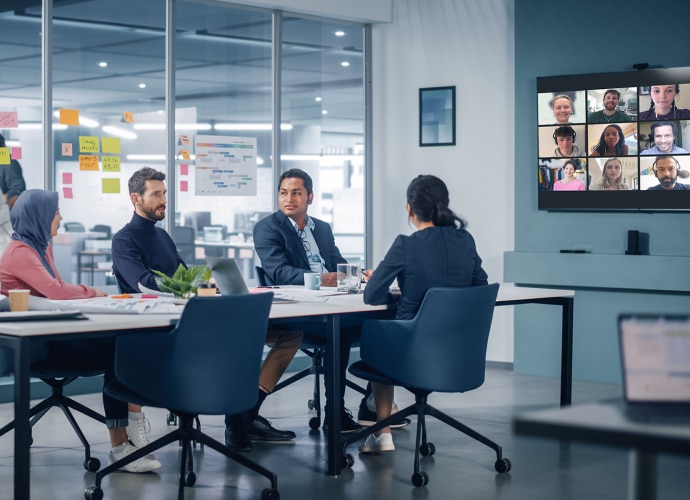 Office meeting with group around a table plus large screen and multiple online participants