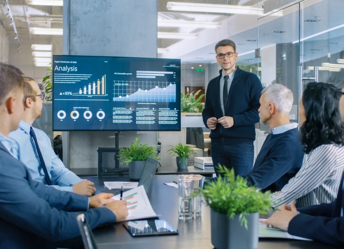 Boardroom with man presenting and business information on display screen