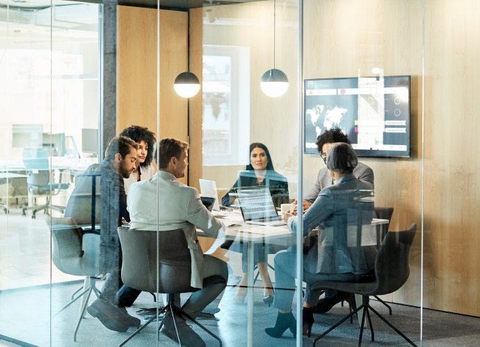 Glass office boardroom with 6 people meeting