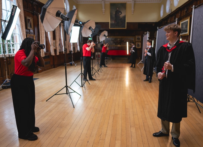 Photographers taking portraits of graduate students in a room