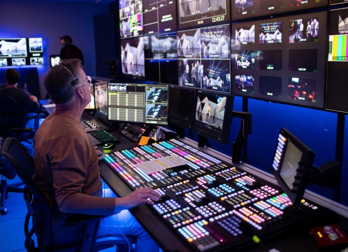 Operator with a production switcher and multiple screens.