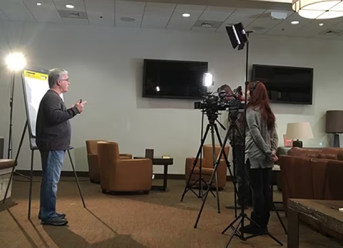 A person giving a presentation in front of a camera and lights.