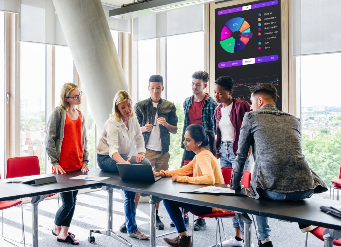 Students talking together in a classroom with a BRAVIA display behind them