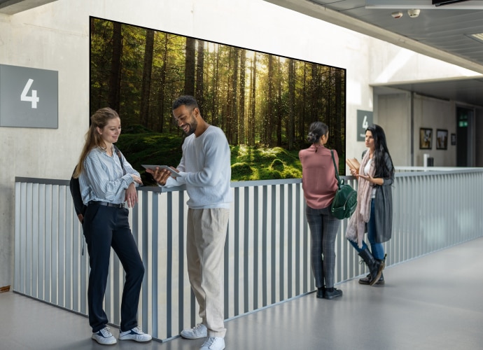 Students chatting in a university hall with a BRAVIA display behind them