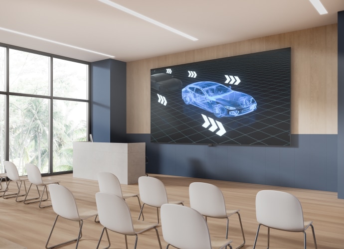 A lecture theater with a BRAVIA display on the wall showing a 3D model of a car