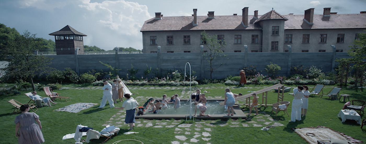 Children playing in the garden with the Nazi concentration camp in the background.