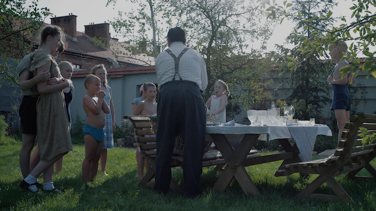 Children gather around a garden table for a meal in the movie The Zone of Interest.