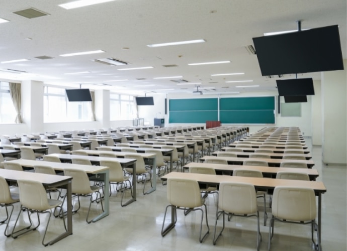 University classroom view with multiple screens, projector and speakers