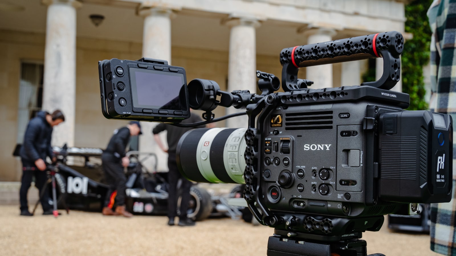 Close-up of BURANO cinema camera with CanAm Shadow racing car and crew in background