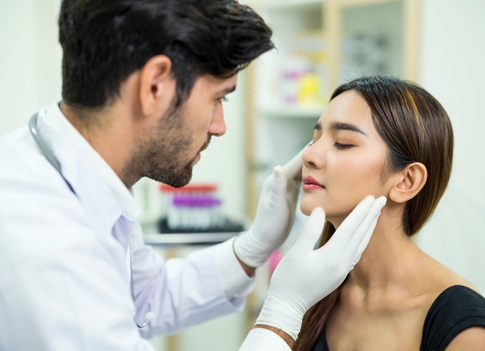 A dermatologist is checking the woman’s skin